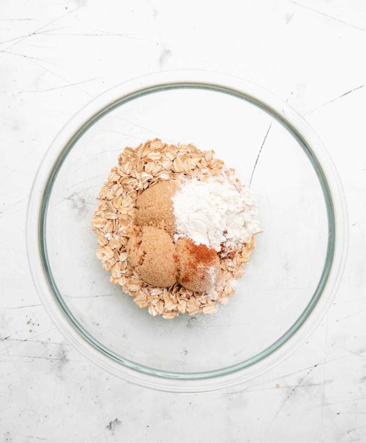 Ingredients for oatmeal topping in a glass mixing bowl. 