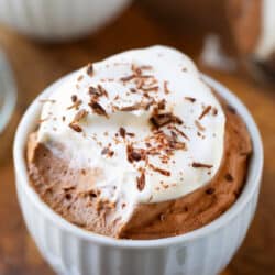 White porcelain cup filled with chocolate mousse and whipped cream.