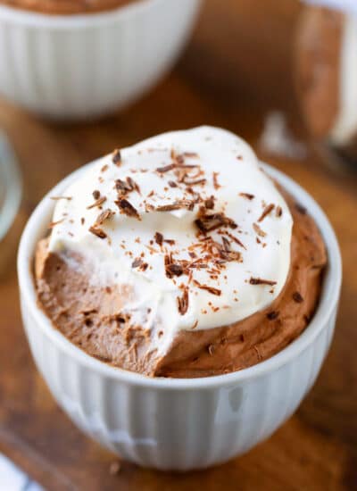 White porcelain cup filled with chocolate mousse and whipped cream.