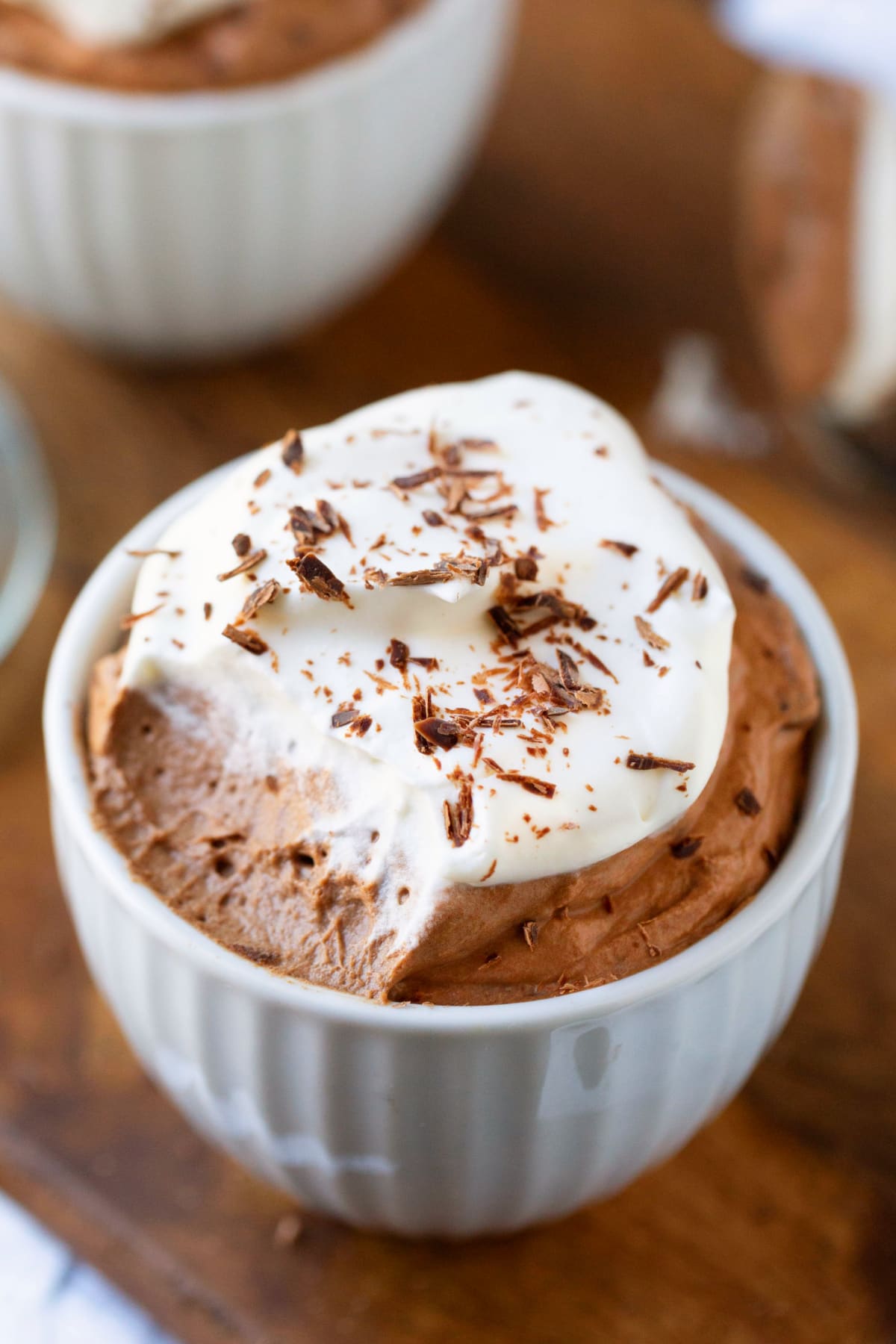 White porcelain cup filled with chocolate mousse and whipped cream.