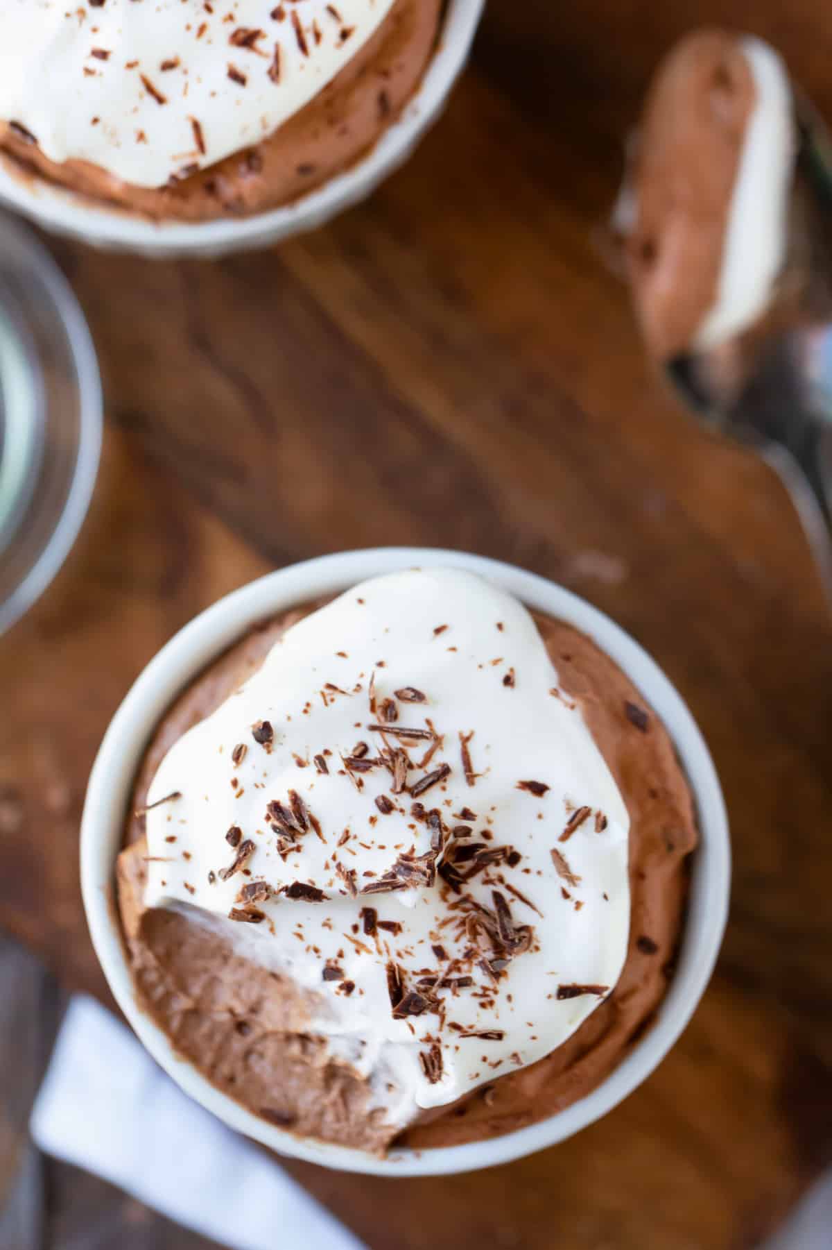 Finished chocolate mousse recipe in white dishes on a wooden cutting board.