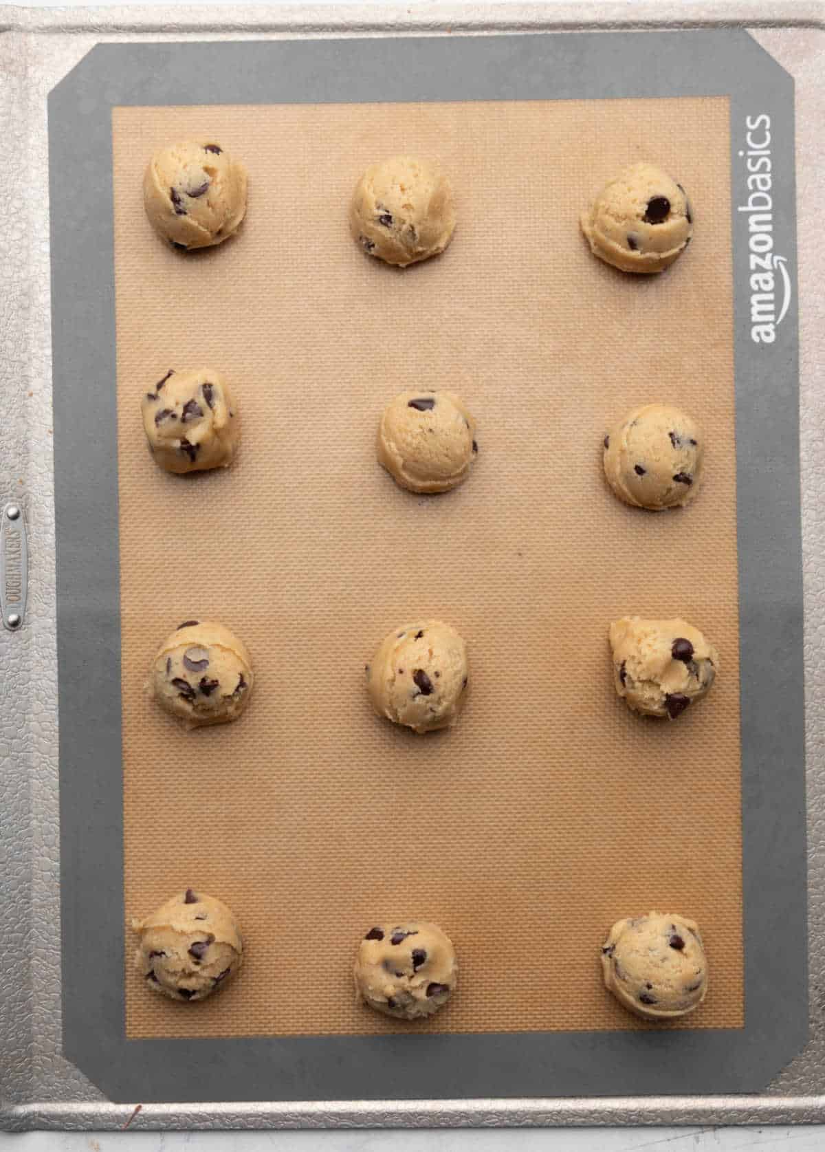Scoops of coconut oil chocolate chip cookie dough on a baking sheet.