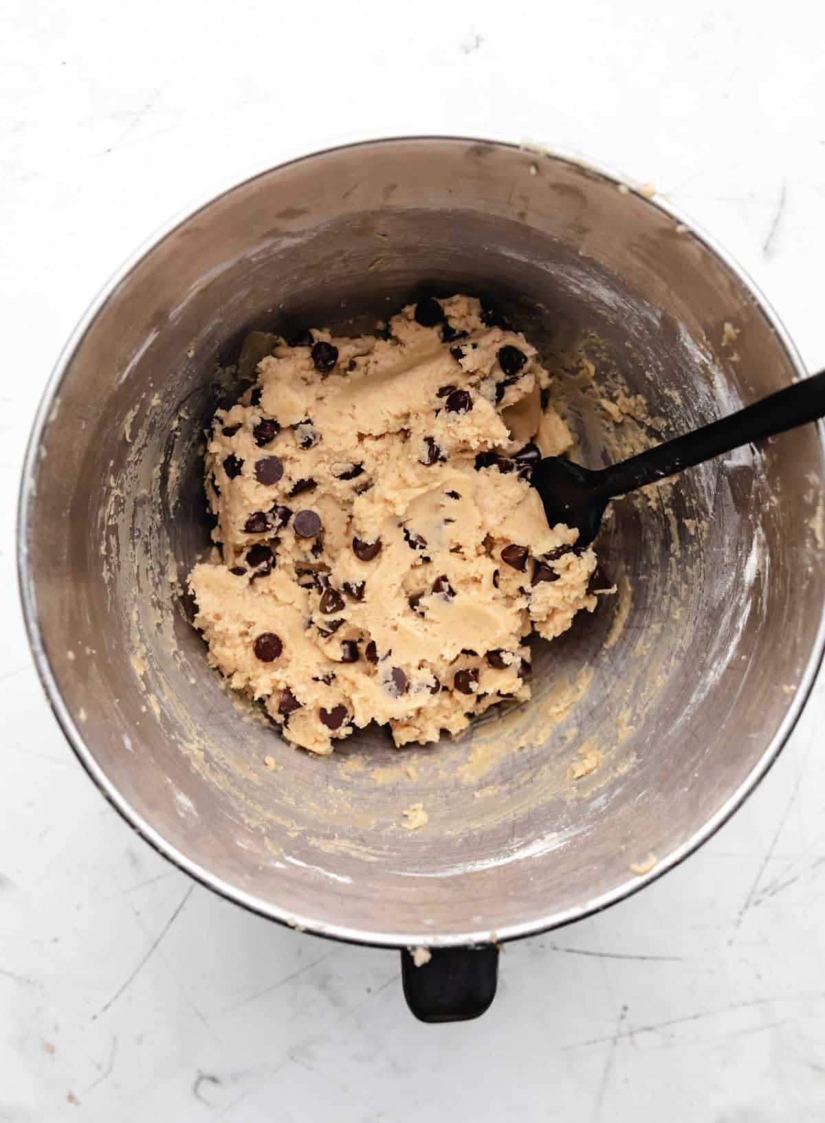 Coconut oil chocolate chip cookie dough in a silver mixing bowl. 