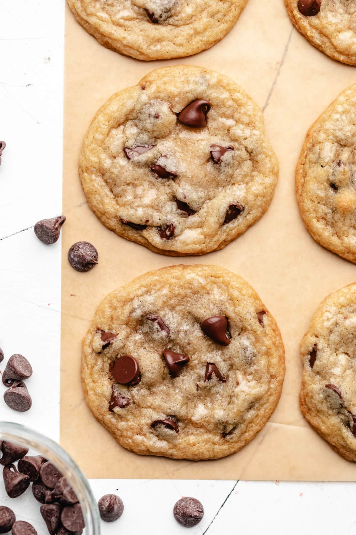 A row of coconut oil chocolate chip cookies on brown parchment paper. 