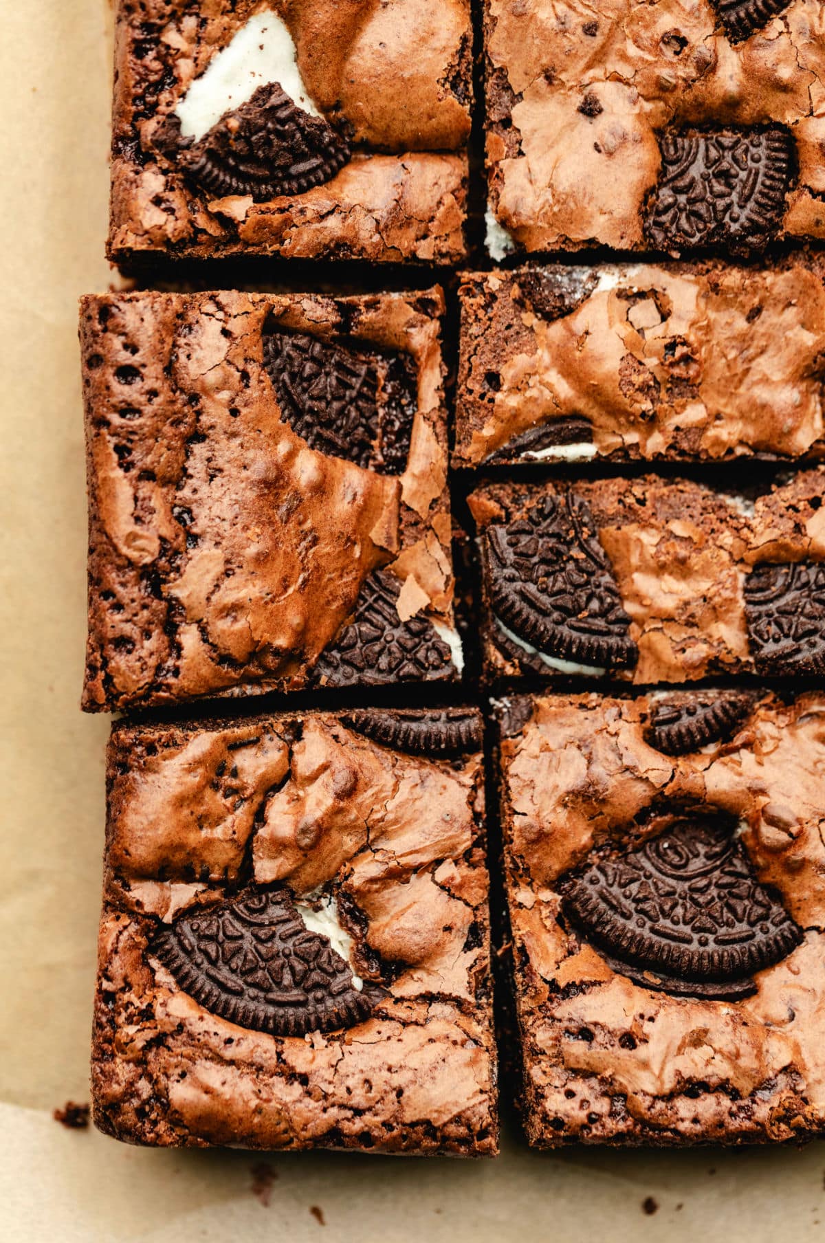 A row of cut Oreo brownies on brown parchment paper. 