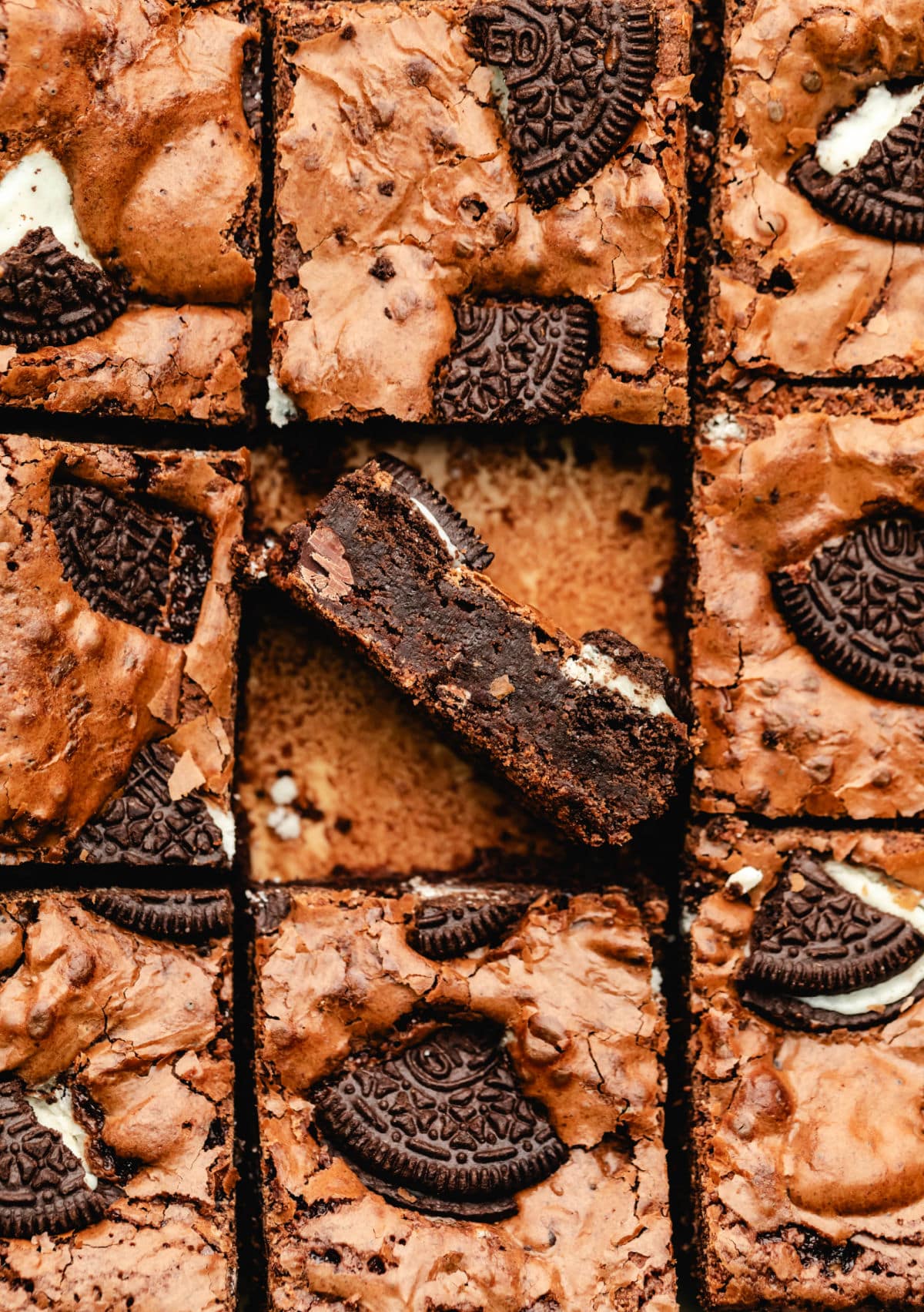 An Oreo brownie turned on its side in the middle of cut brownies. 