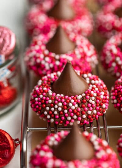 A row of Valentine's Day kiss cookies on a wire cooling rack.