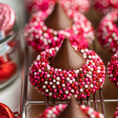 A row of Valentine's Day kiss cookies on a wire cooling rack.