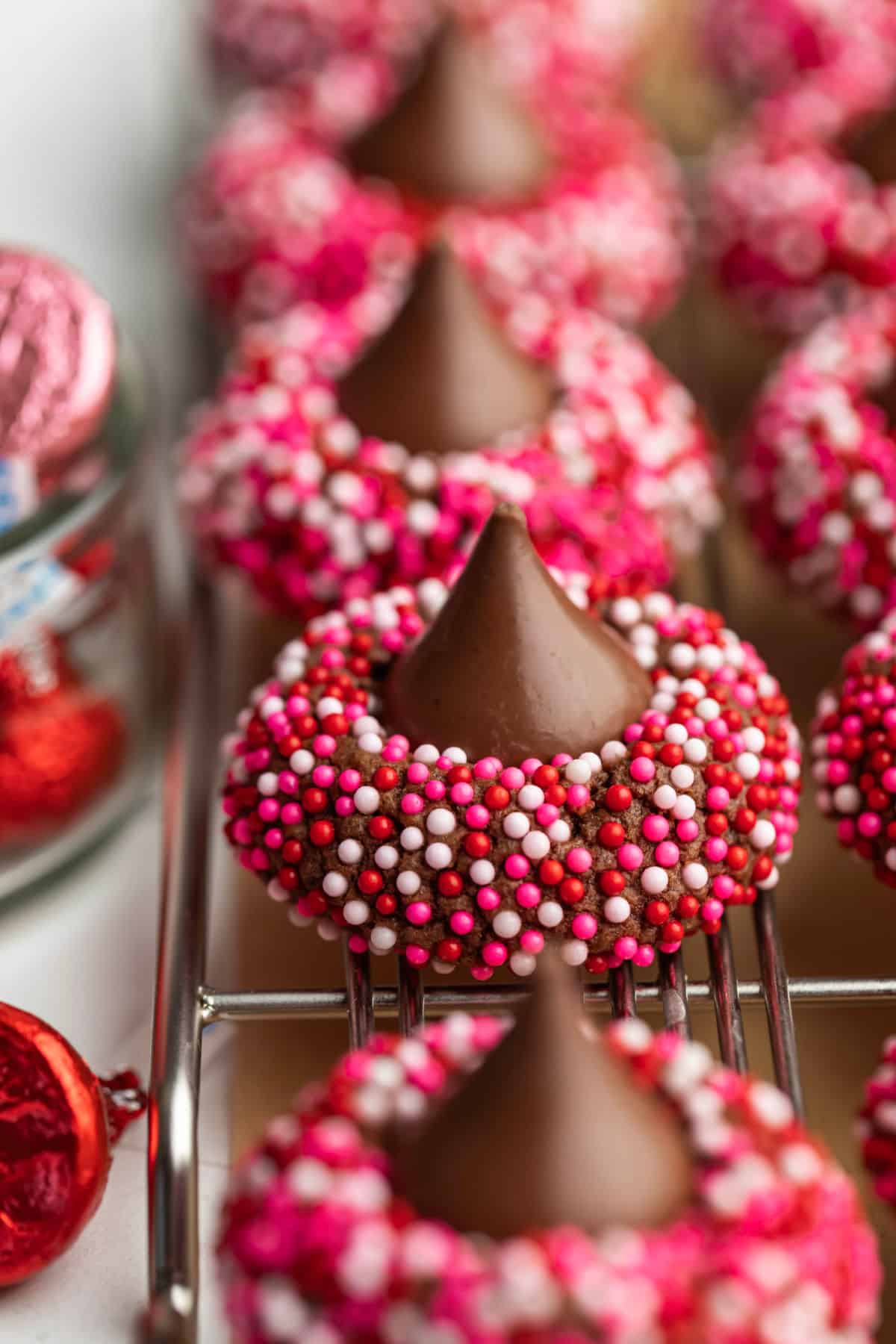 A row of Valentine's Day kiss cookies on a wire cooling rack.