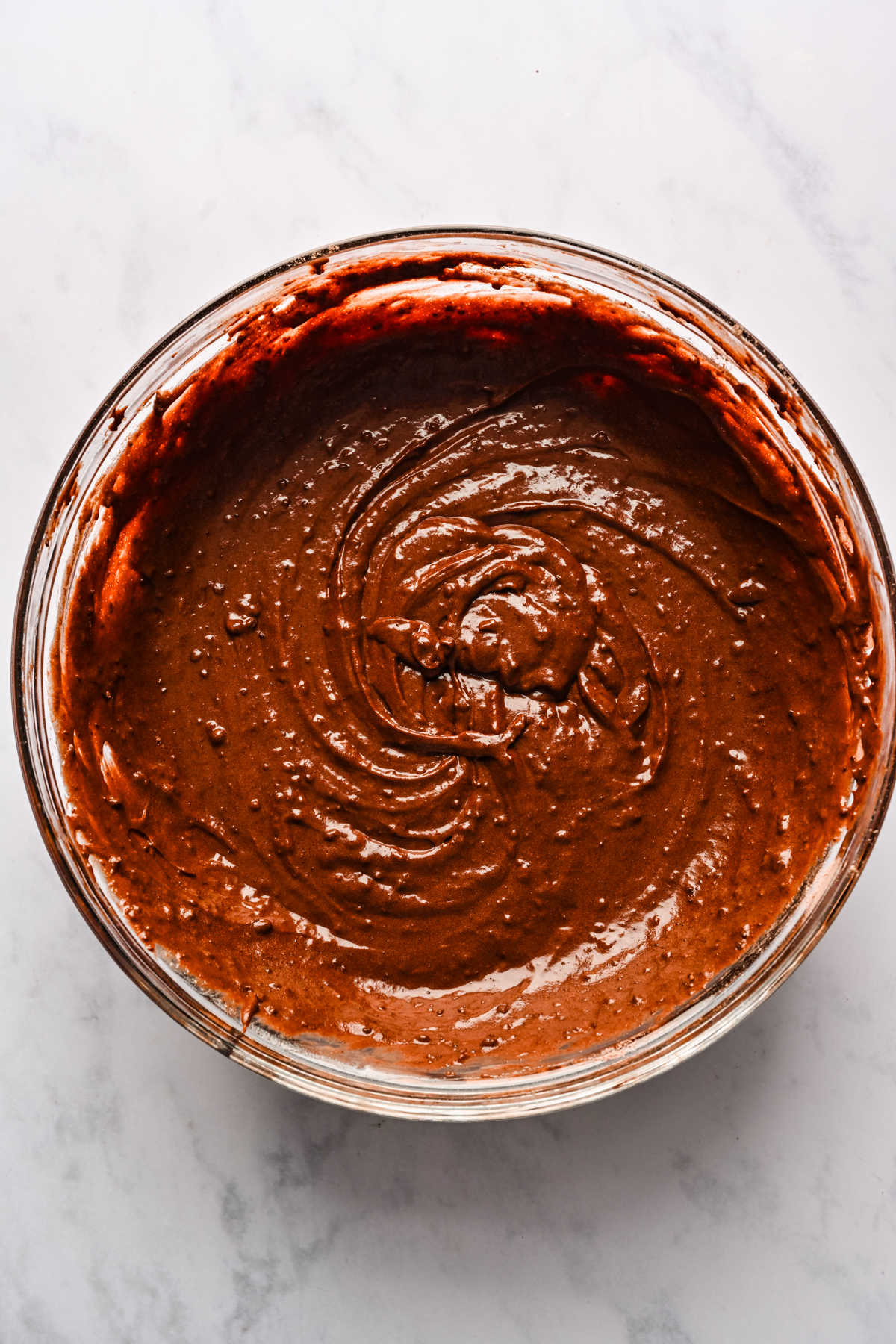 Chocolate brownie cake batter in a glass mixing bowl. 