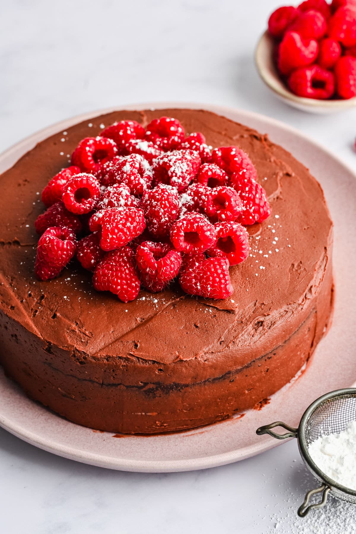 Frosted chocolate brownie cake topped with raspberries and powdered sugar. 