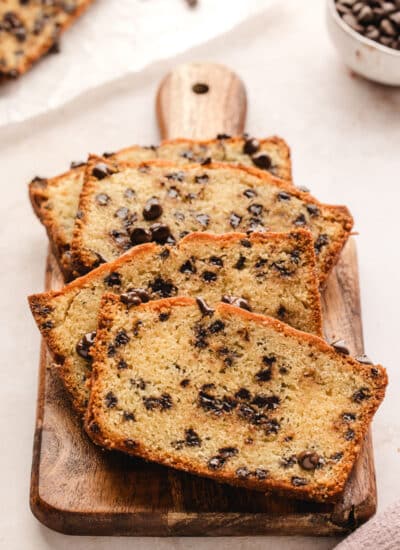 Slices of chocolate chip loaf cake on a wooden cutting board.