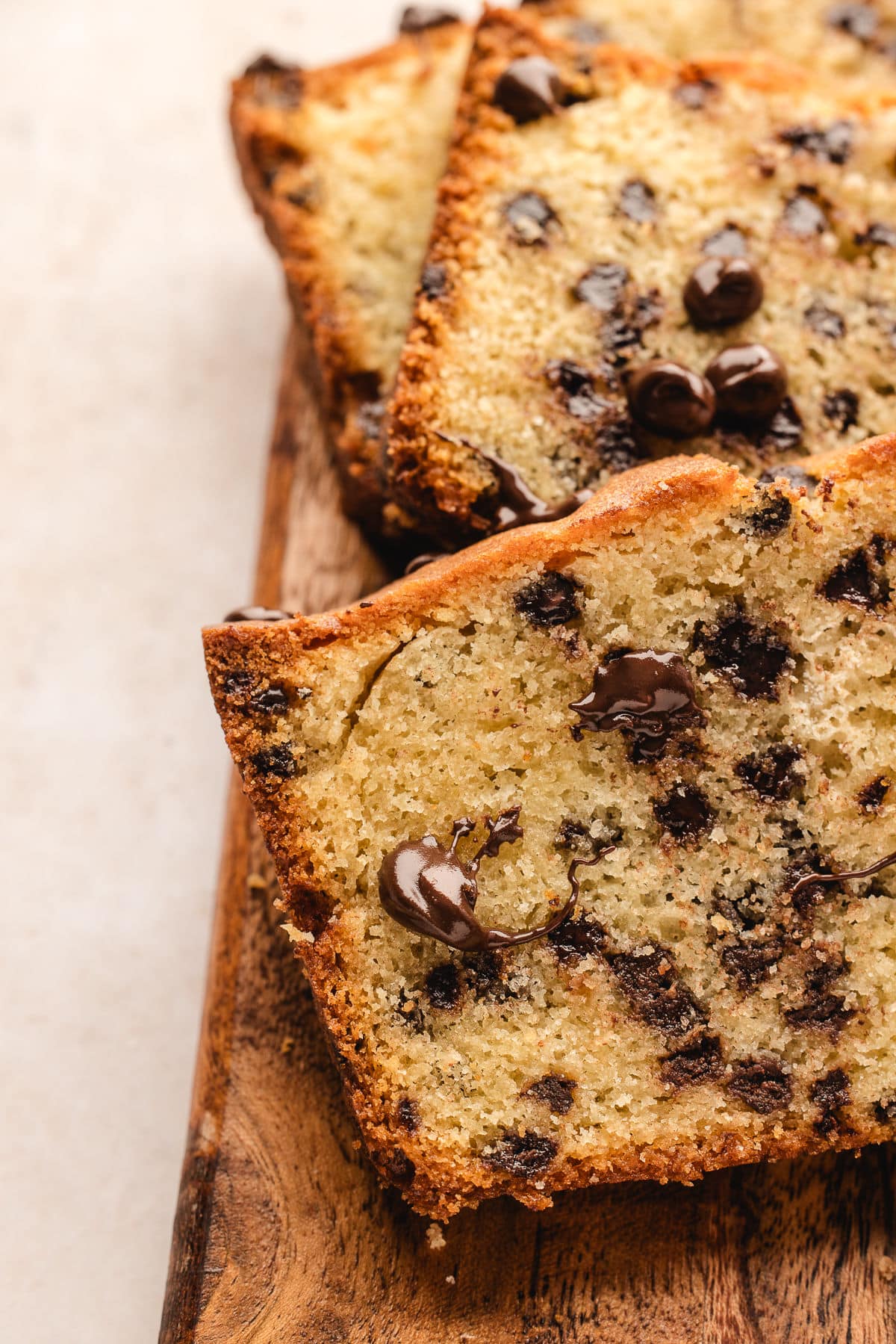 Close up photo of melting chocolate chips in a piece of chocolate chip loaf cake. 