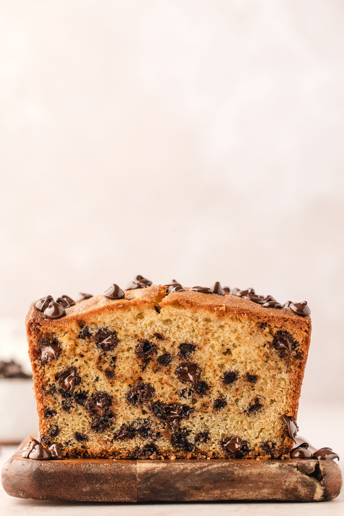 A cut chocolate chip loaf cake on a wooden cutting board.