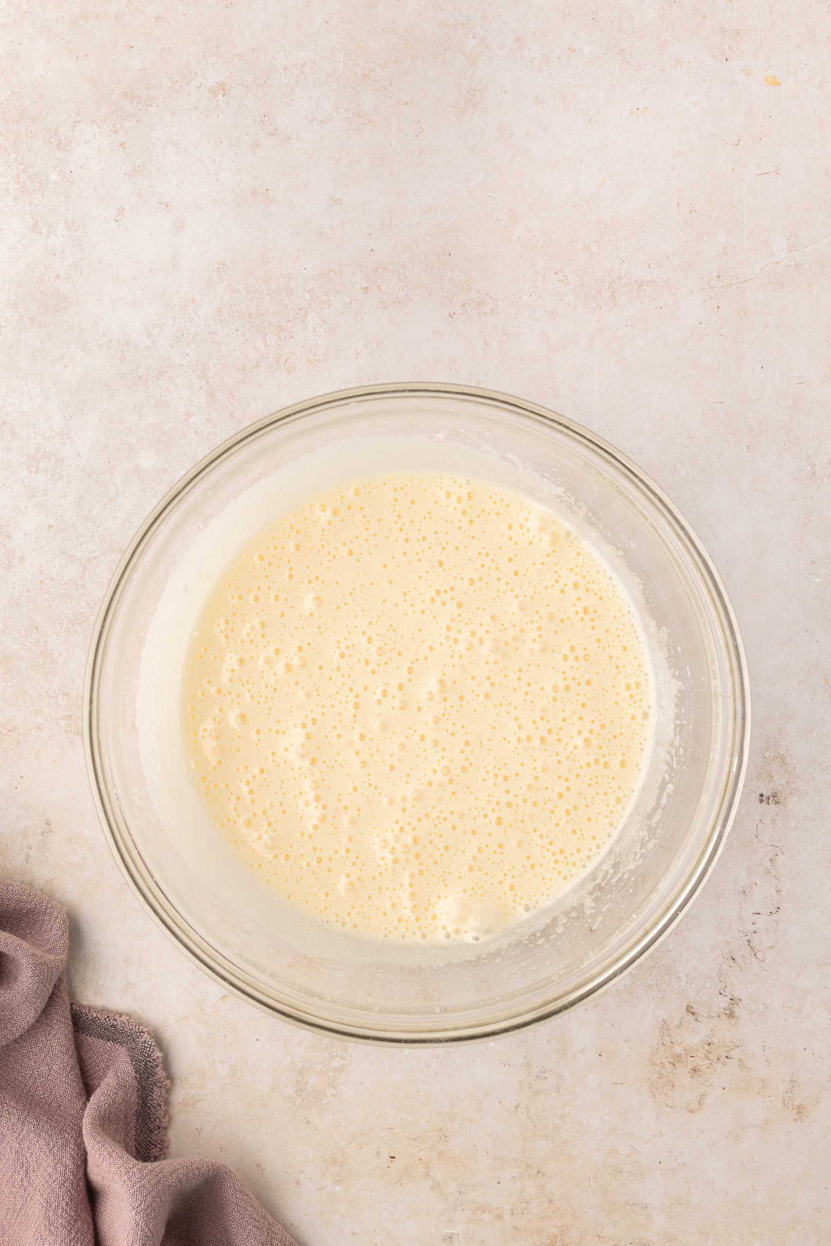 Eggs and sugar beaten together in a glass mixing bowl. 