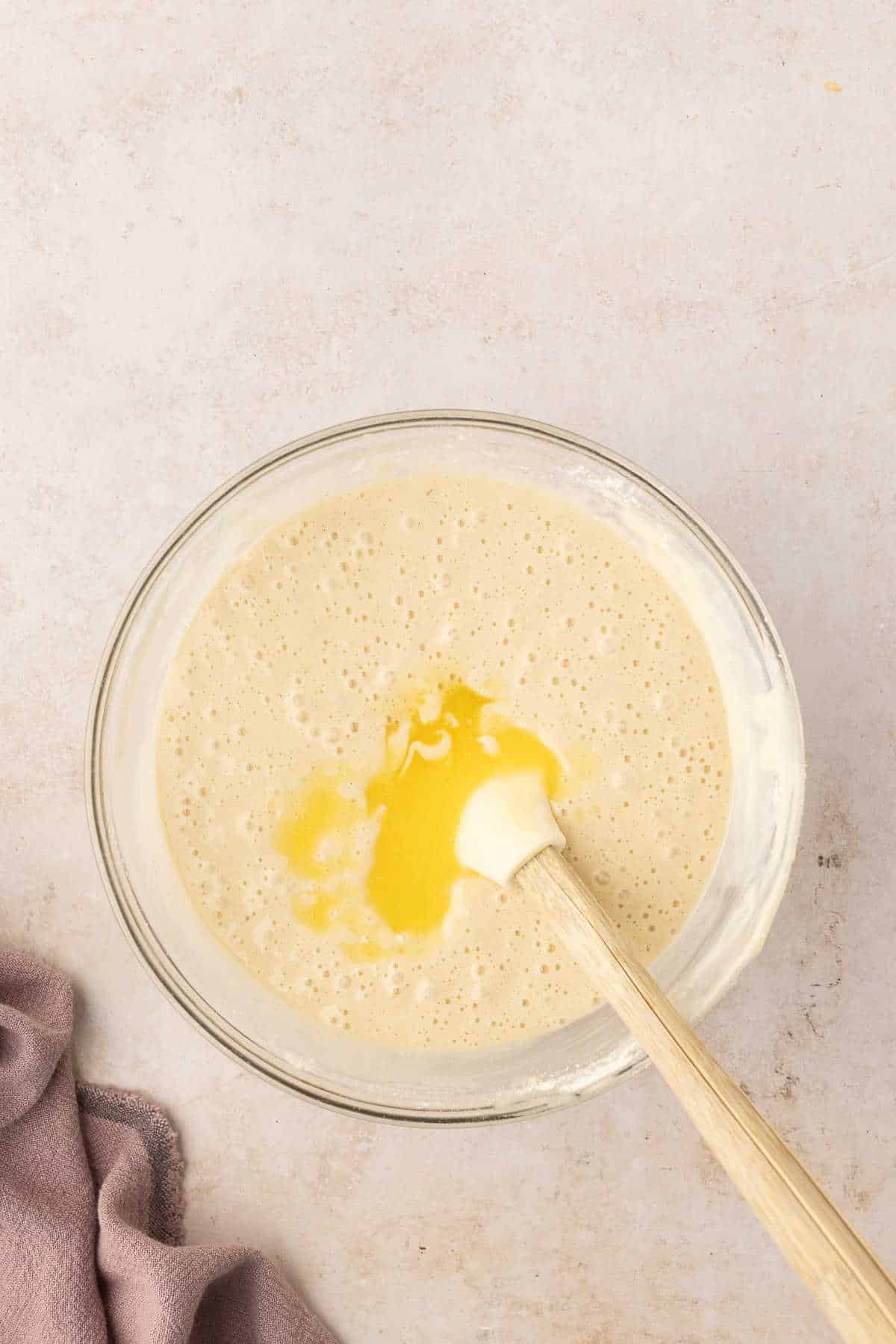 A spatula stirring butter into chocolate chip loaf cake batter. 