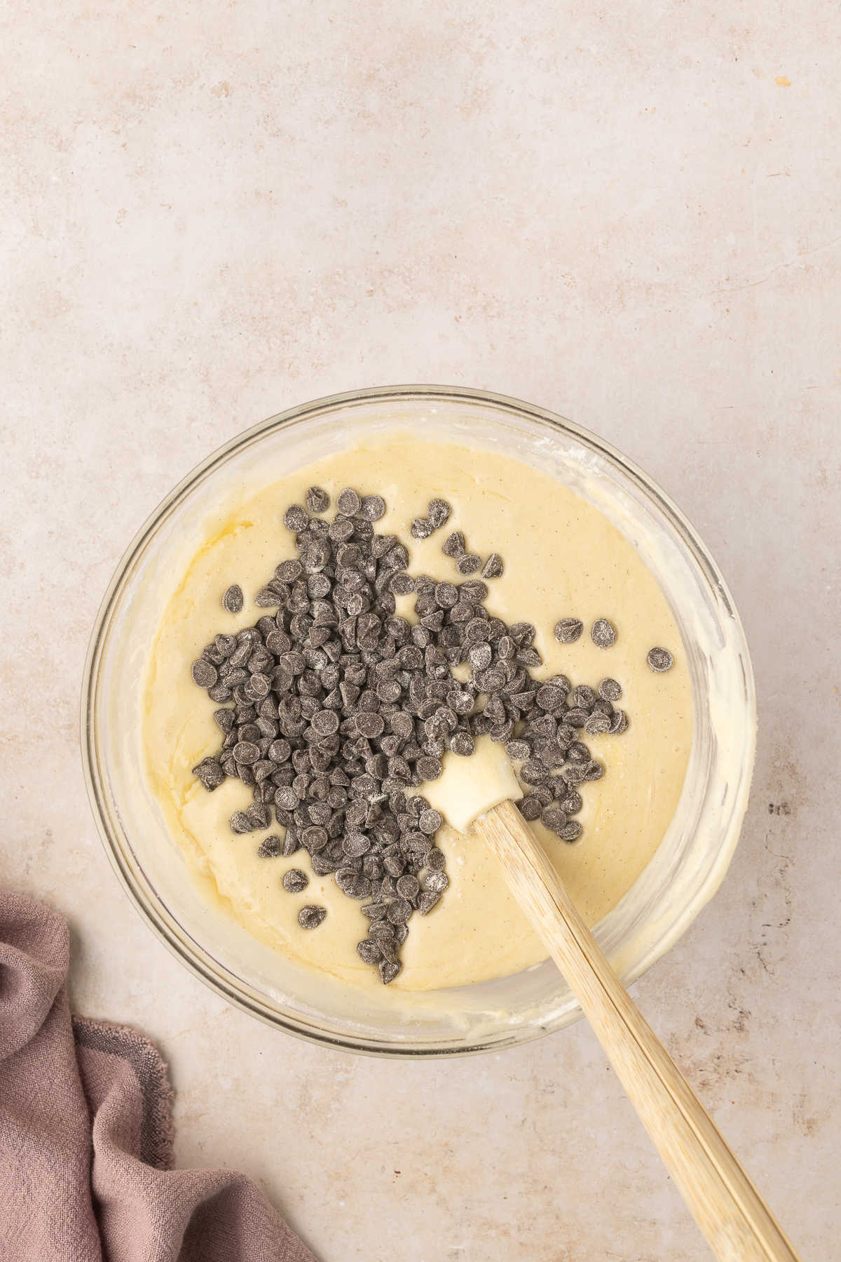 A spatula stirring chocolate chips into loaf cake batter.