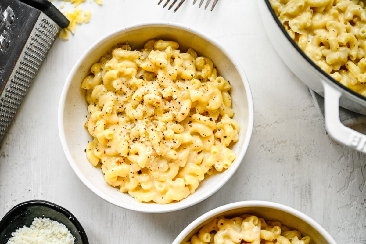 Dishes of gouda mac and cheese next to a cheese grater.