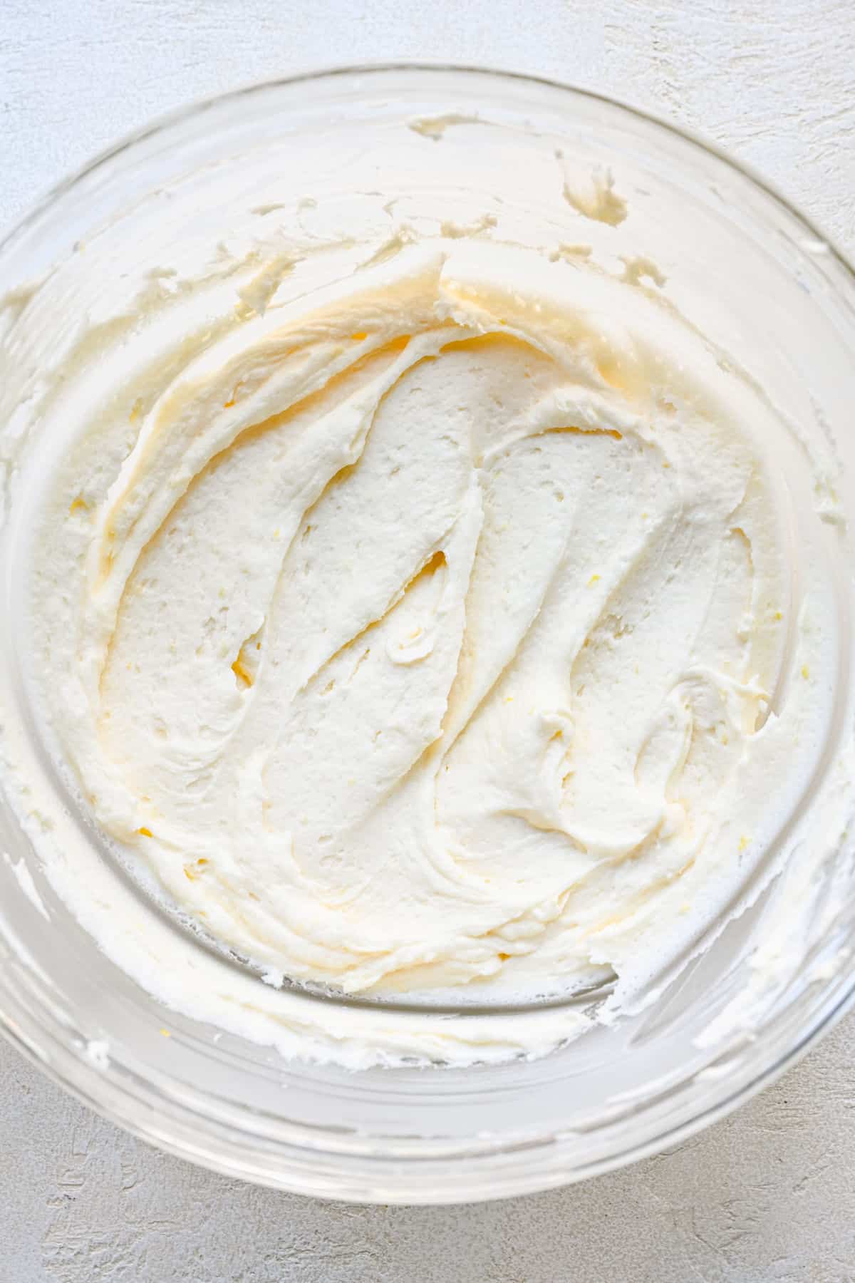 Lemon buttercream frosting in a glass mixing bowl.