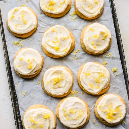 A tray of lemon sugar cookies next to a dish of fresh lemon zest.