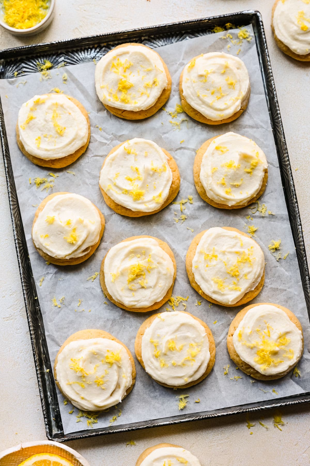 A tray of lemon sugar cookies next to a dish of fresh lemon zest. 