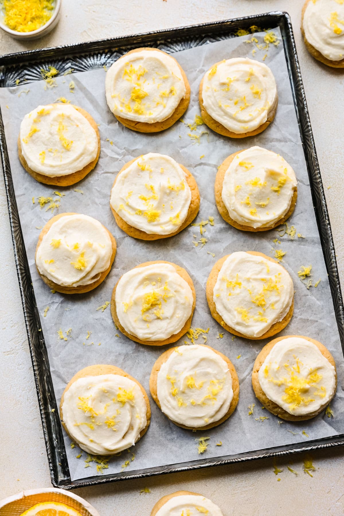 A tray of lemon sugar cookies next to a dish of fresh lemon zest.