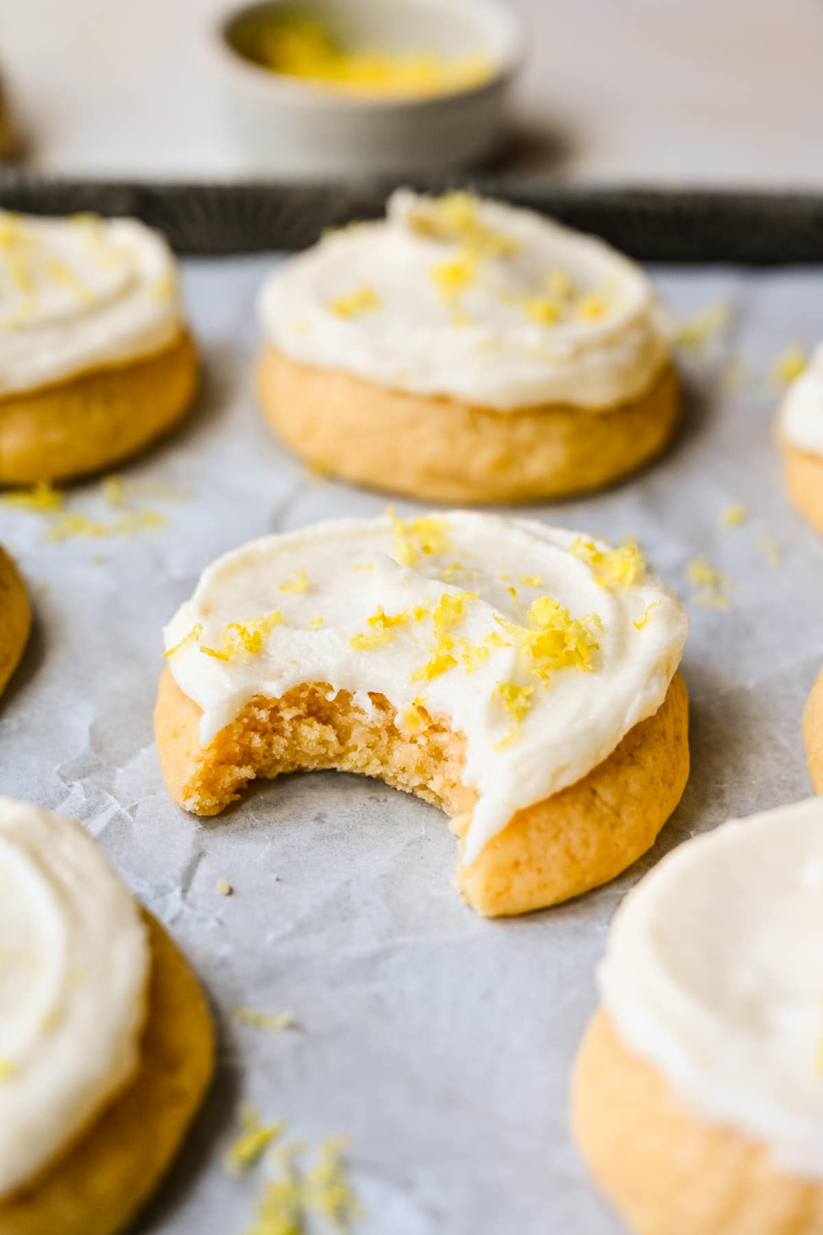 A frosted lemon sugar cookie with a bite missing.