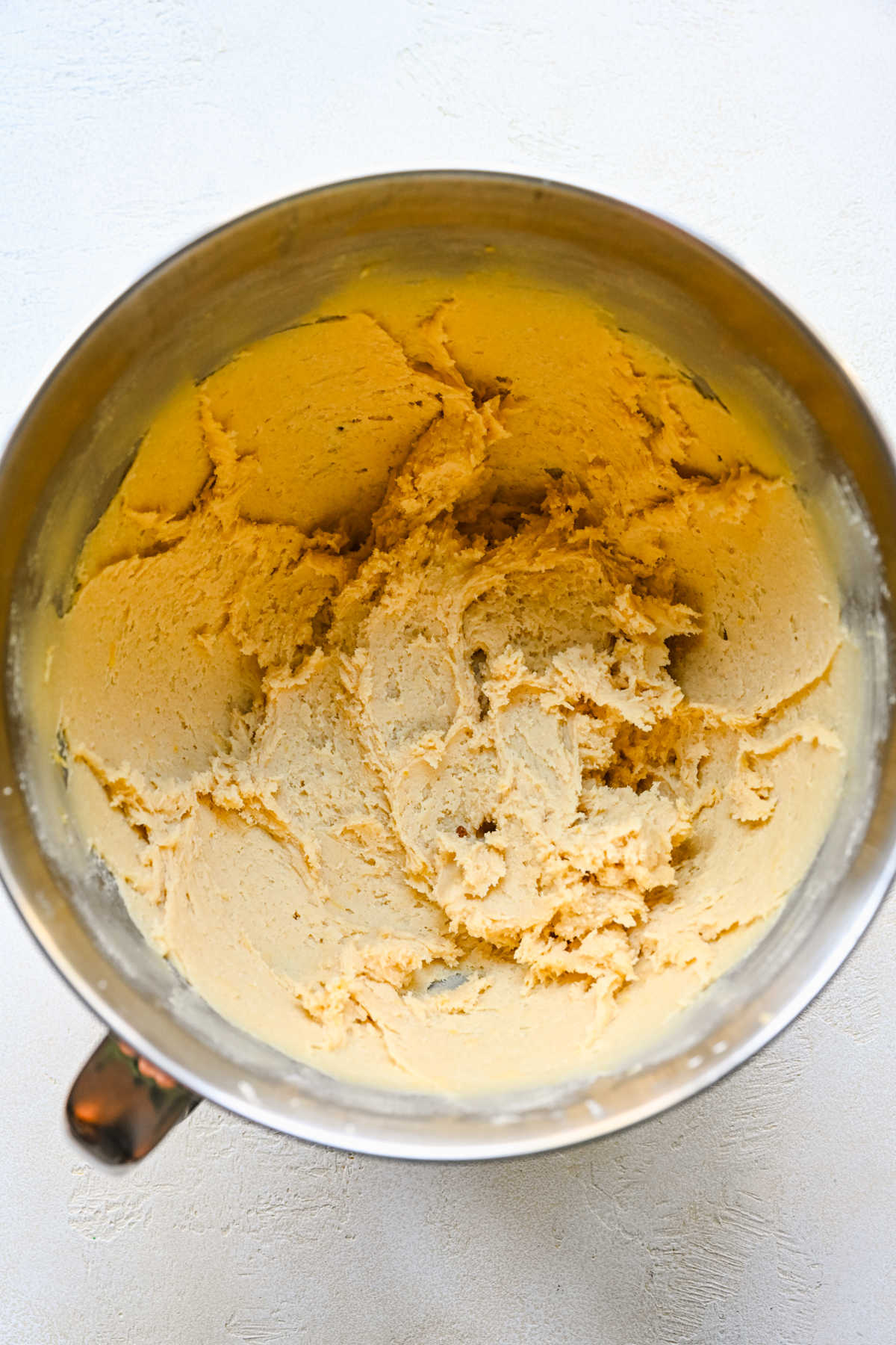 Lemon sugar cookie dough in a silver mixing bowl. 