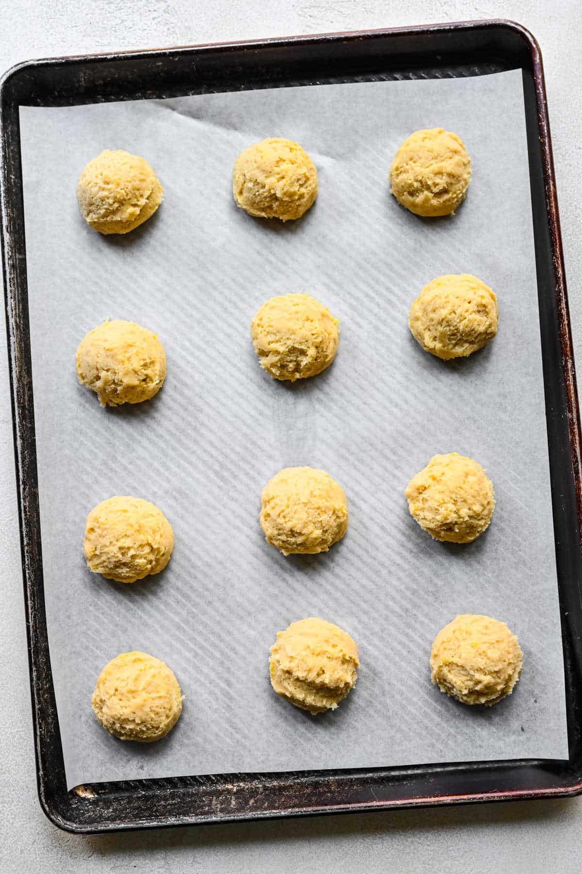 Scoops of lemon cookie sugar dough on a baking sheet. 