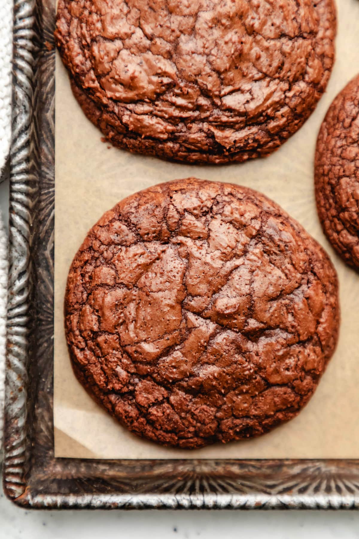 A brownie cookie at the bottom edge of a vintage baking sheet. 