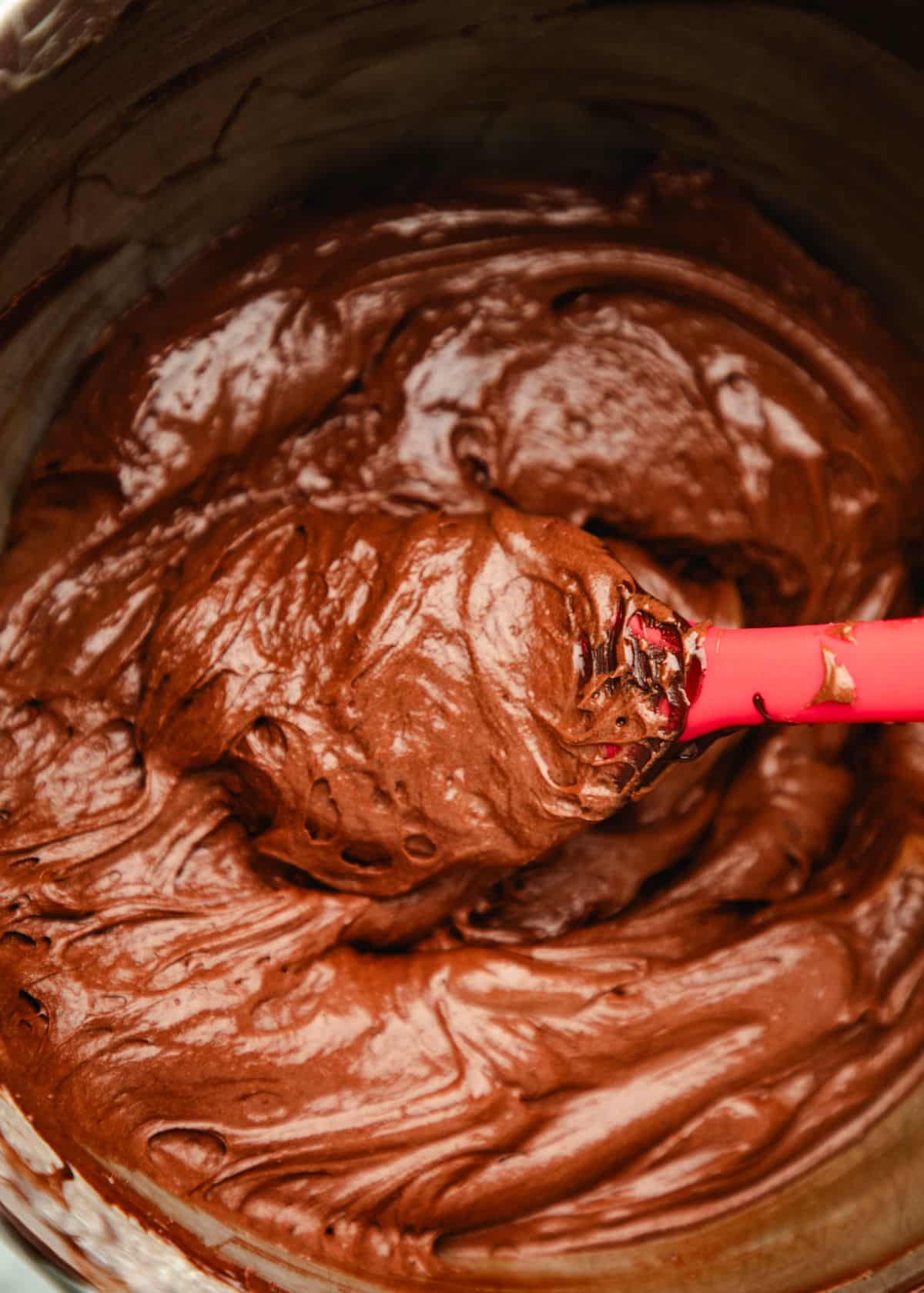 A spatula holding a scoop of chocolate egg mixture. 