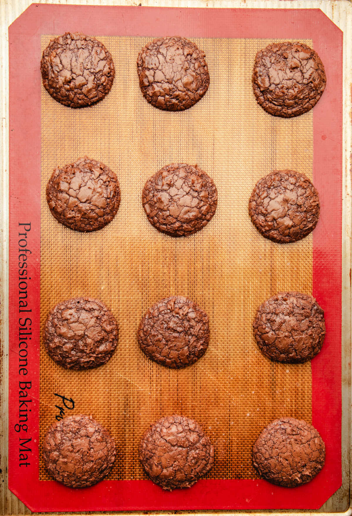 Baked brownie cookies on a silicone baking mat. 