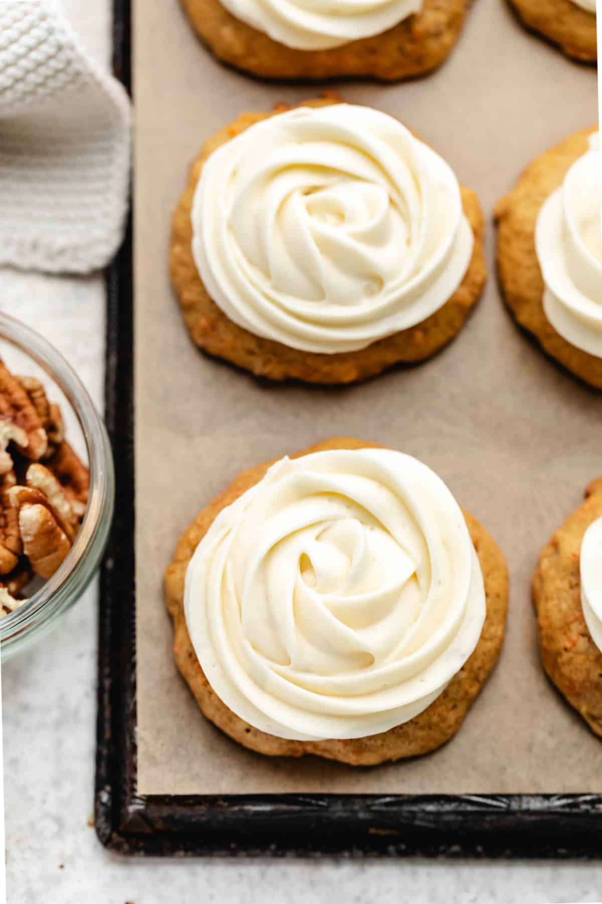 A row of carrot cake cookies topped with cream cheese frosting piped in a rosette.