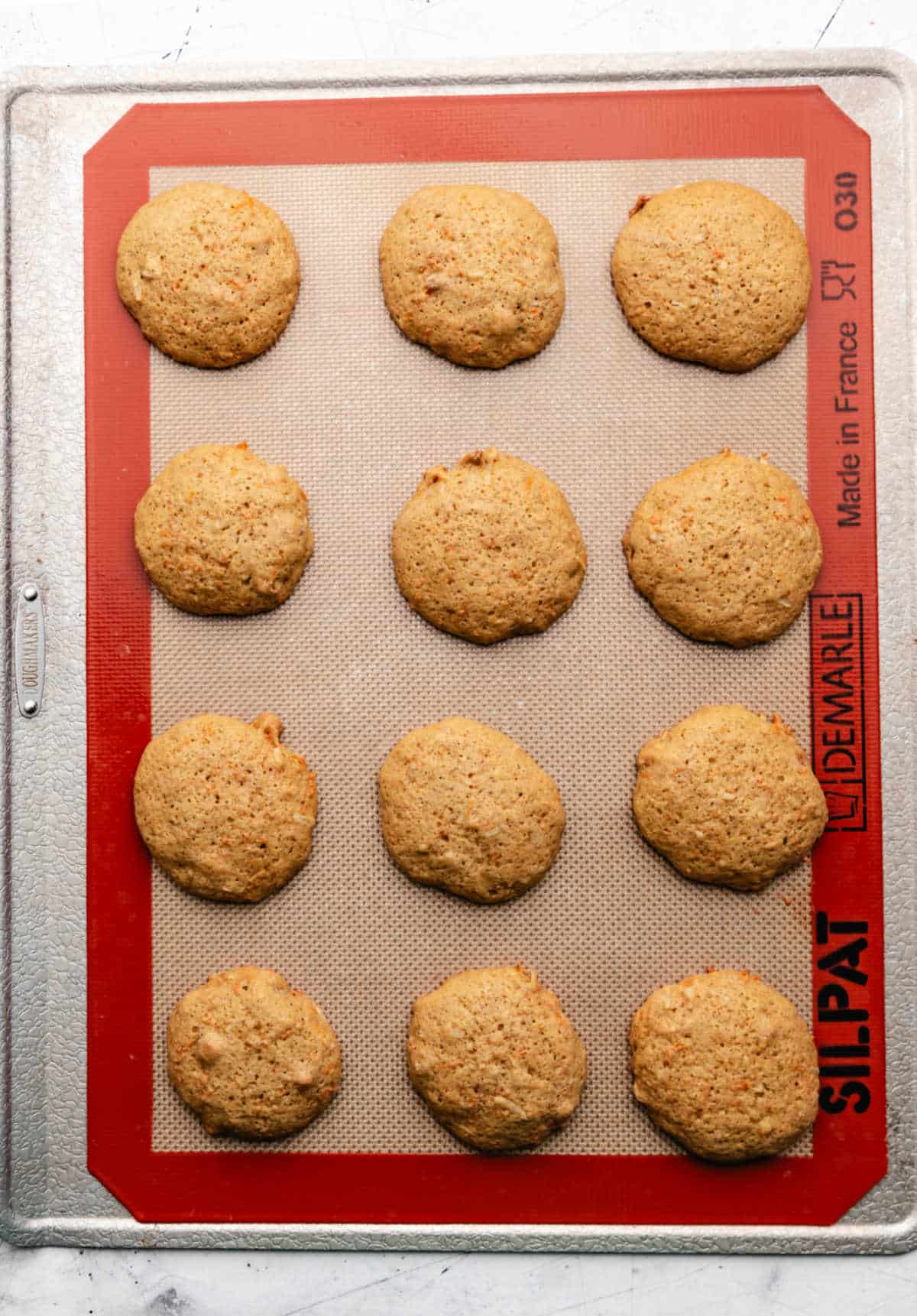 Baked carrot cake cookies on a baking sheet. 