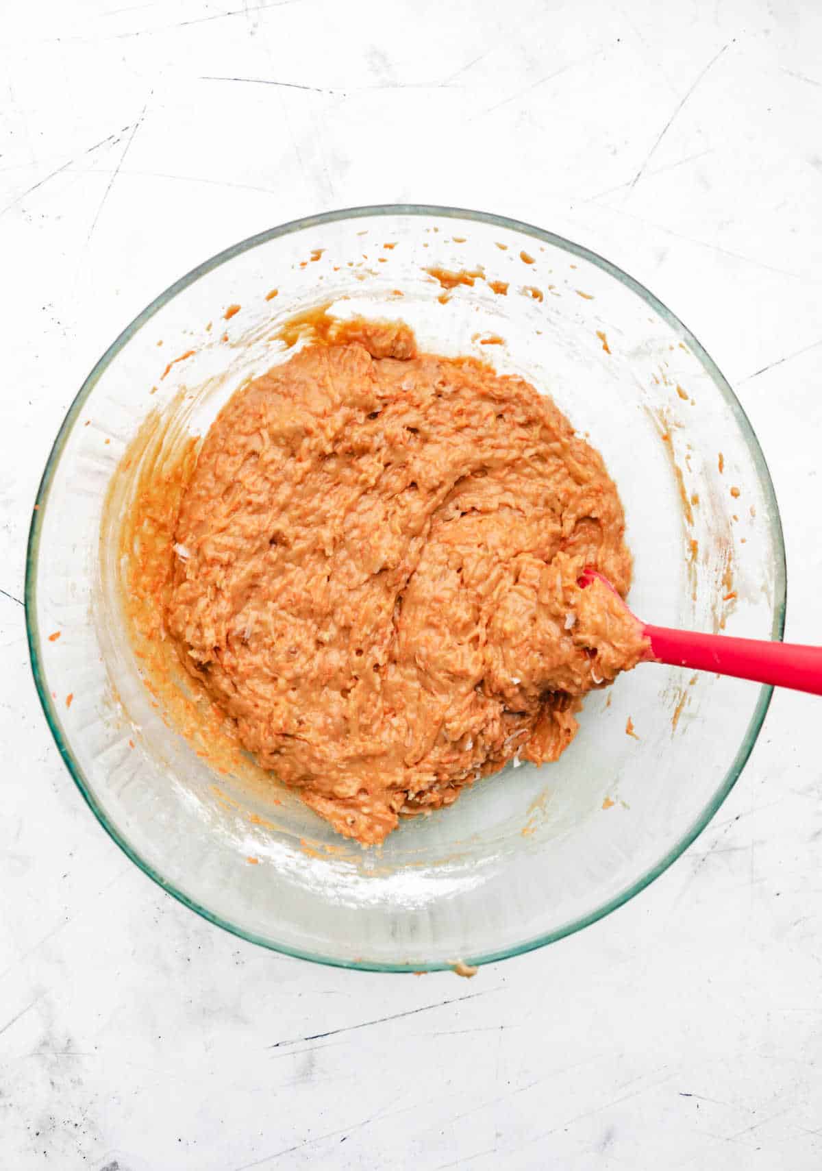 Carrots coconut and nuts stirred into carrot cake cookie batter.