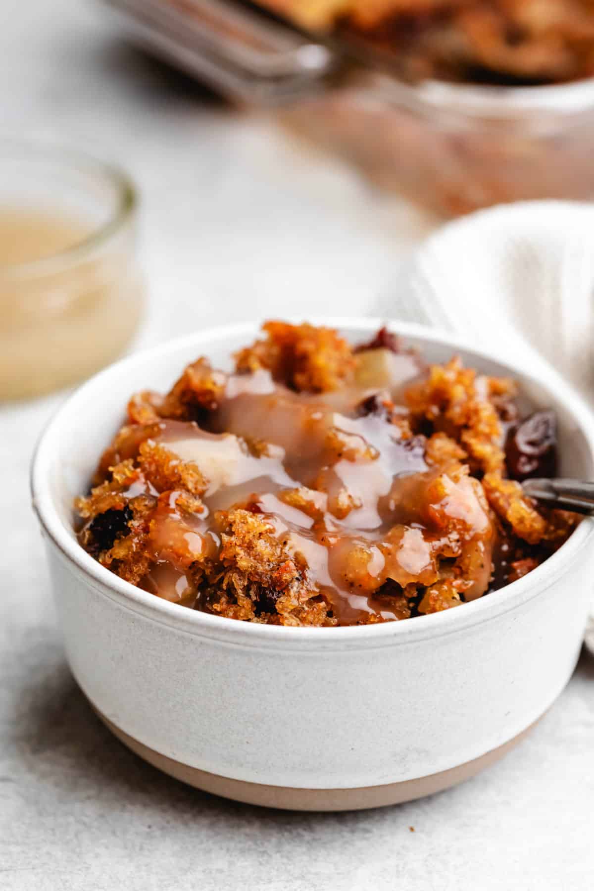 A dish of carrot pudding next to a dish of vanilla sauce. 