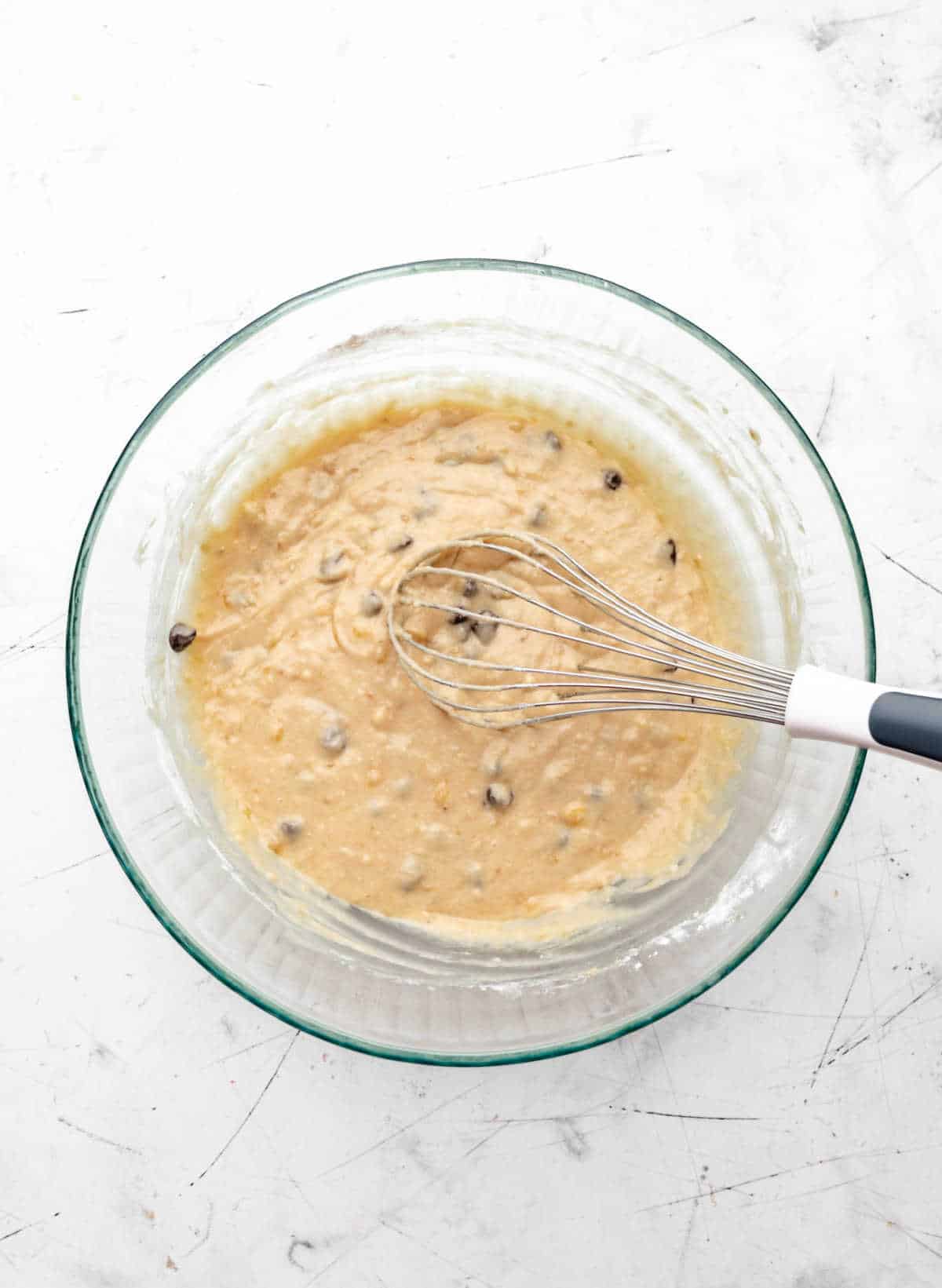 Chocolate chip banana bread batter in a glass mixing bowl. 