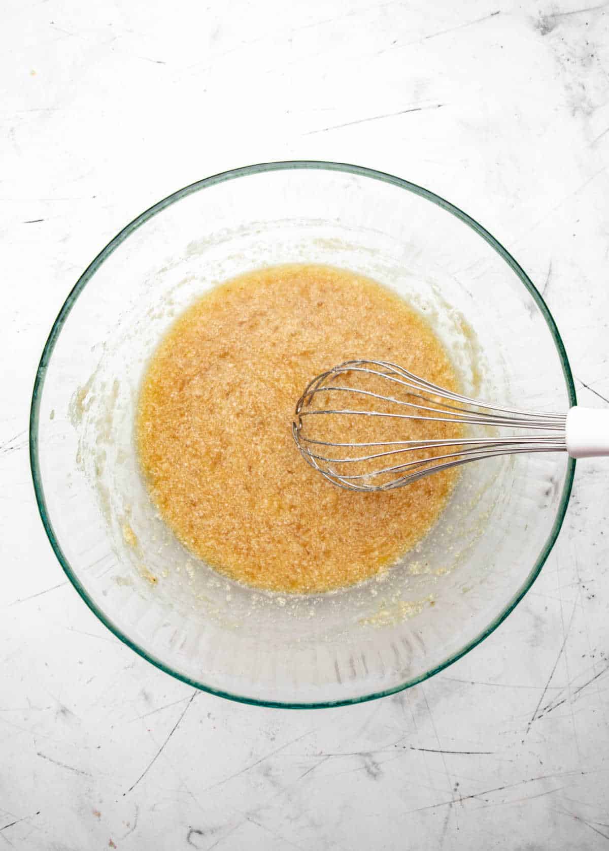 Egg and vanilla mixed into banana mixture in a glass mixing bowl. 