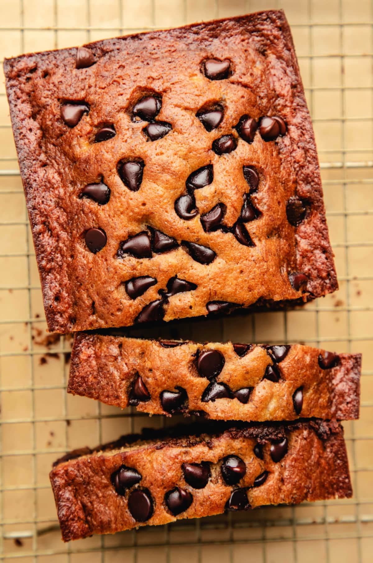 A loaf of chocolate chip banana bread with two cut slices leaning against it. 