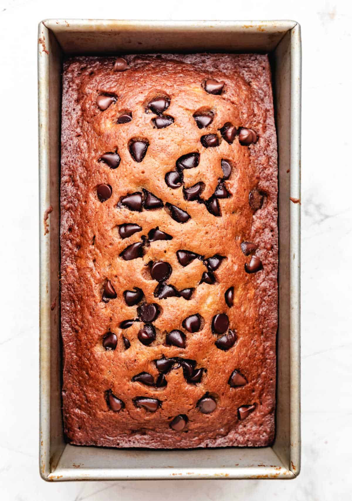A baked loaf of chocolate chip banana bread in a loaf pan.
