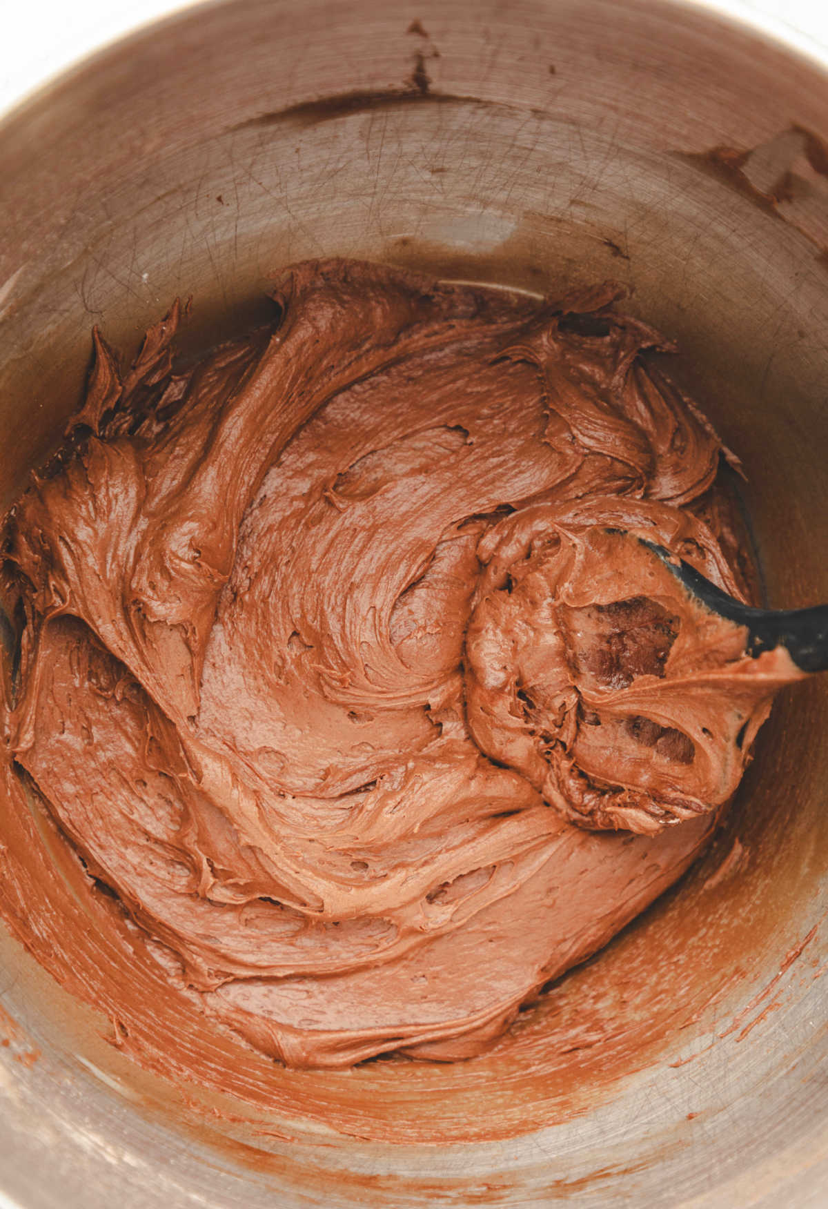 Chocolate cream cheese frosting in a silver mixing bowl. 