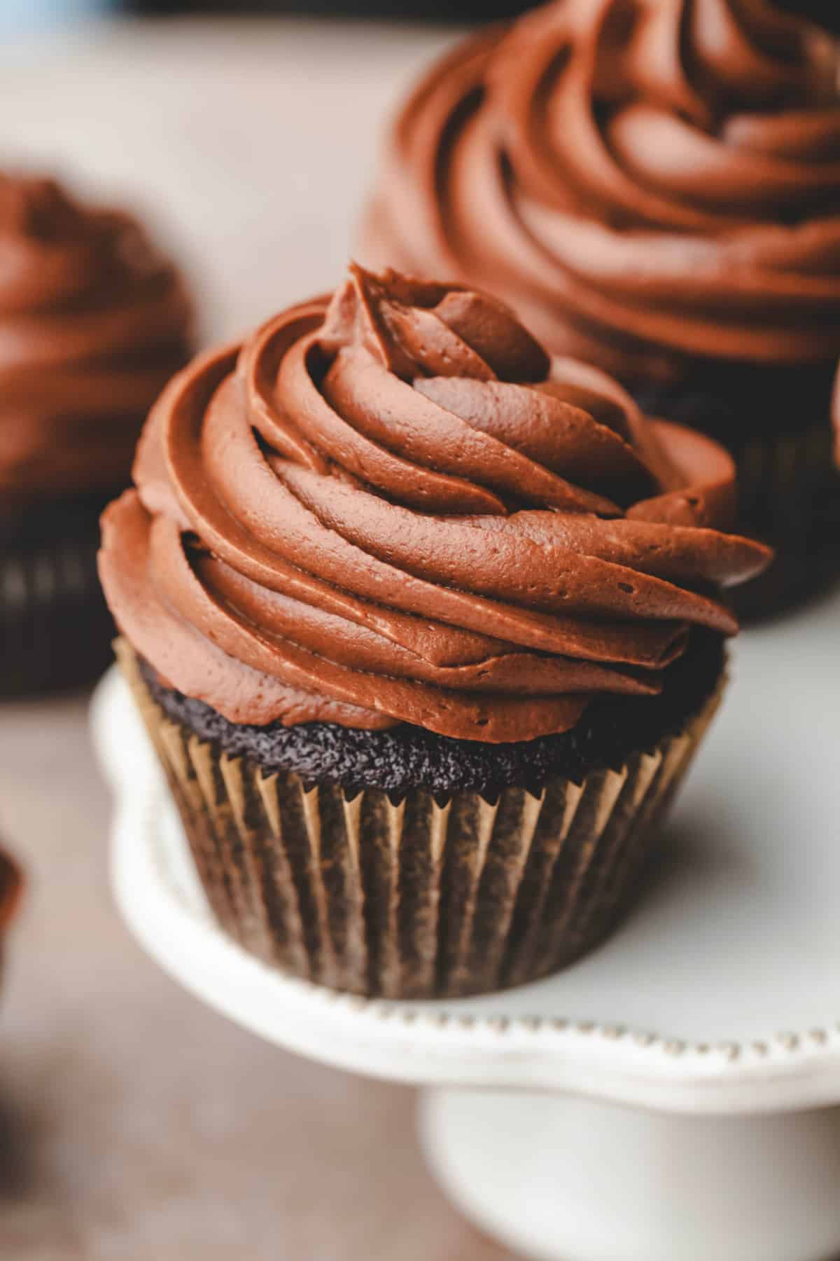 Top view of a chocolate cupcake in a parchment wrapper frosted with chocolate cream cheese frosting.