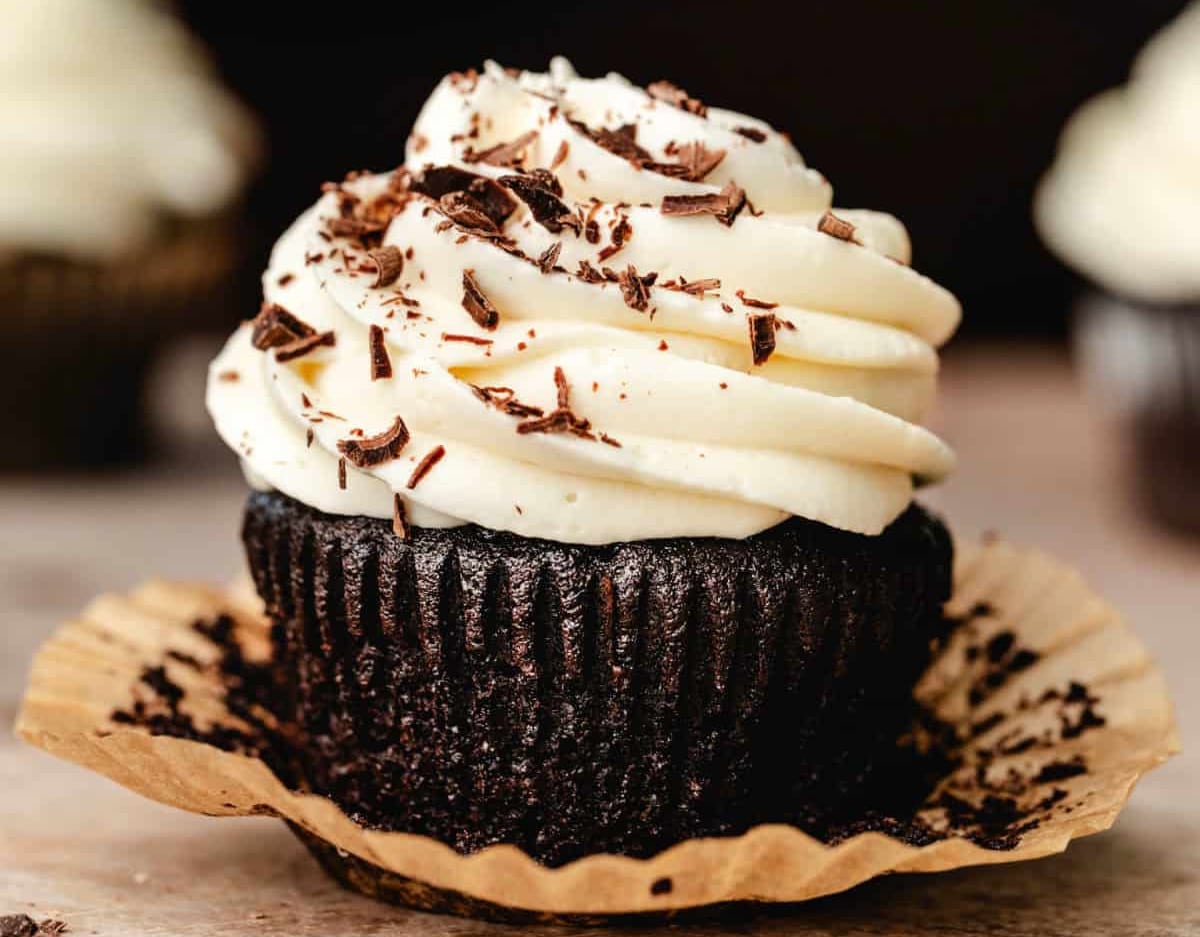 Close up photo of a guinness cupcake topped with cream cheese frosting and chocolate shavings.