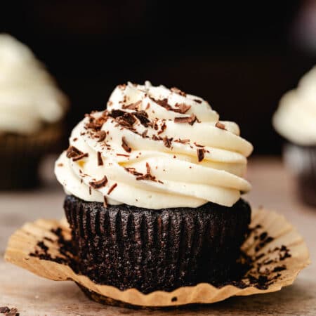 A Guinness cupcake topped with cream cheese frosting and shaved chocolate.