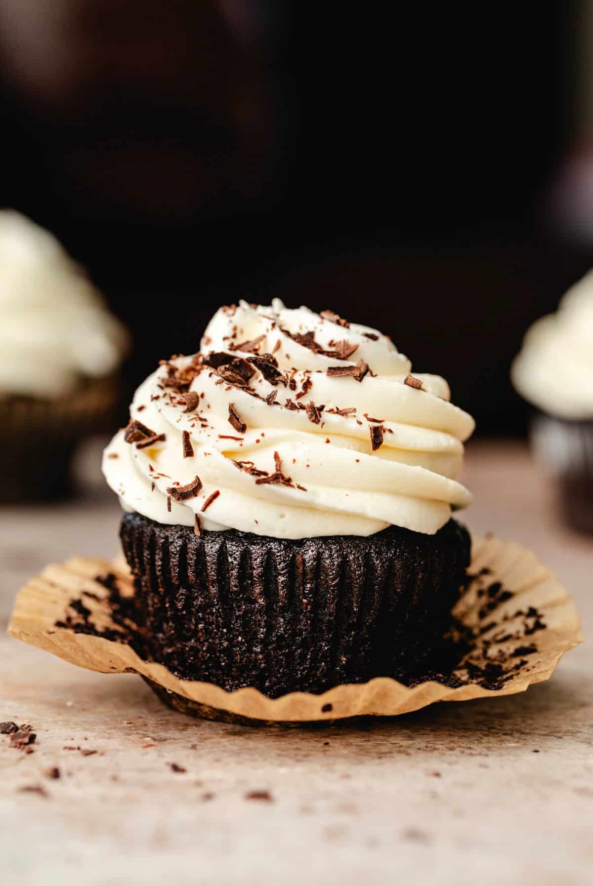 A Guinness cupcake topped with cream cheese frosting and shaved chocolate.