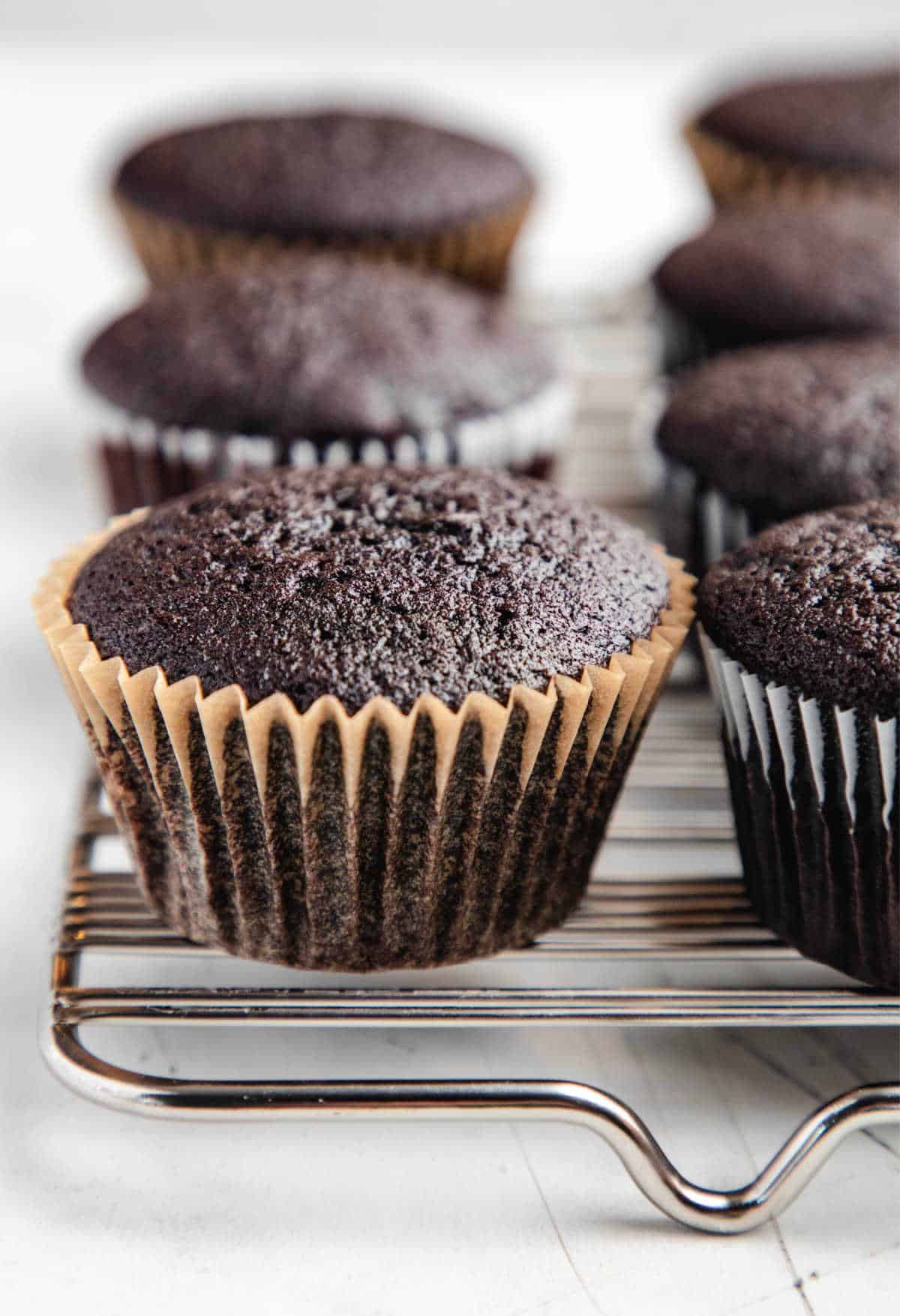 Unfrosted Guinness cupcakes on a wire cooling rack.