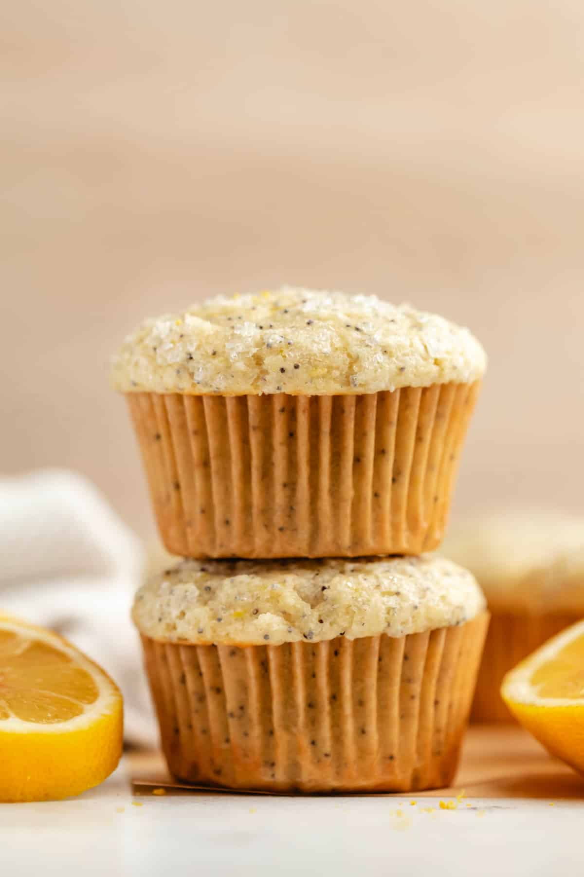 Two lemon poppy seed muffins with sliced lemons on either side. 