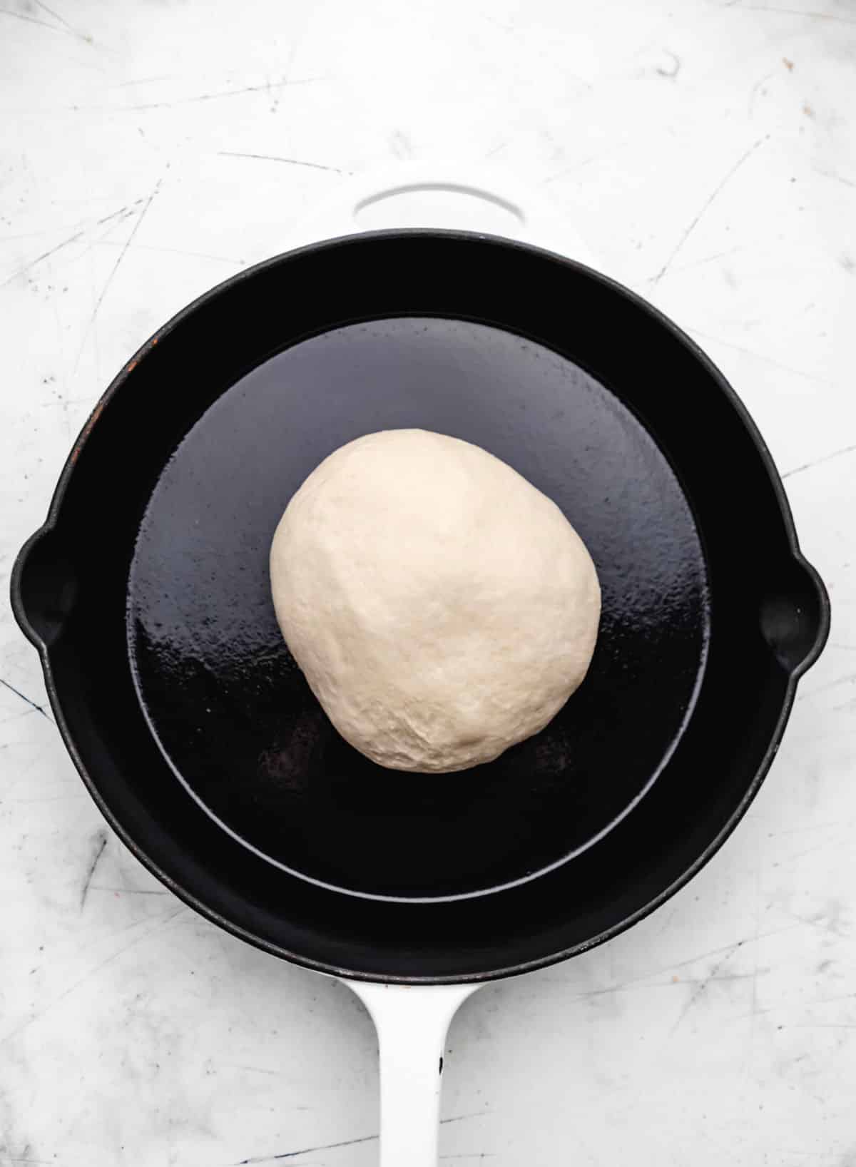A ball of skillet bread dough in a skillet. 