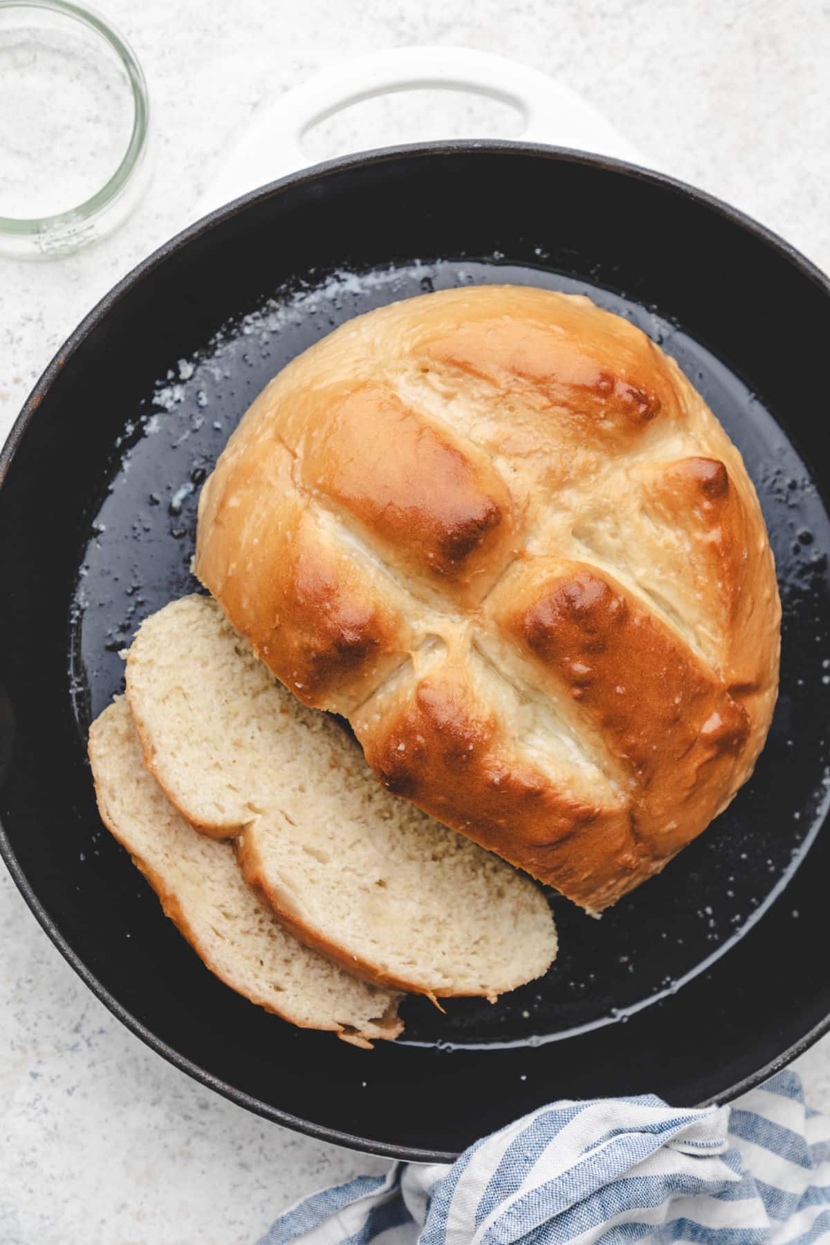 A loaf of skillet bread with two pieces sliced in a skillet.