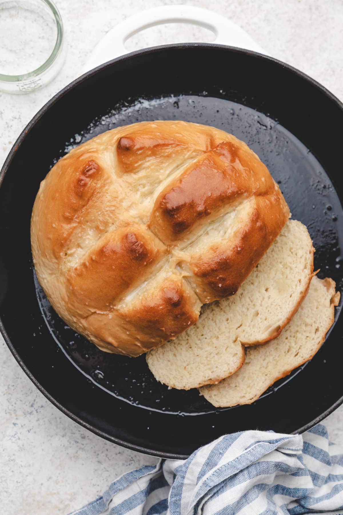 A partially sliced loaf of skillet bread next to the slices. 